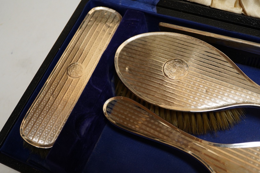 A George V silver six piece engine turned dressing table set Birmingham, 1922 Carringon & Co, comprising hand mirror, pair hairbrushes, pair clothes brushes and a mounted tortoiseshell comb, initialled, in a fitted case